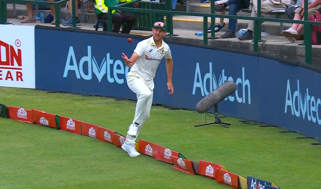 A cricketer throws the ball back into play while completing a catch