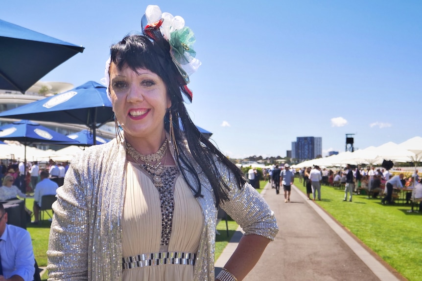 A woman in a sparkly outfit smiles at the Melbourne Cup