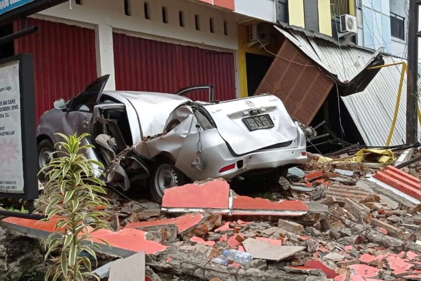 A damaged car and buildings are seen following an earthquake in Mamuju.
