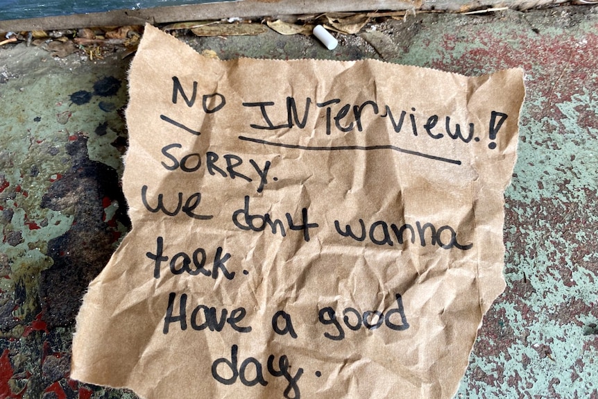 A note on the ground which says "no interview! sorry we don't wanna talk, have a good day".