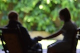 An out-of-focus shot of an elderly man holding a young girl's hand on a deck outside.