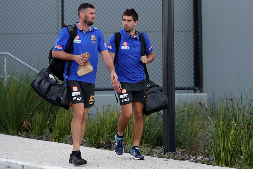 West Coast Eagles players Jack Darling and Andrew Gaff walk while carrying bags.