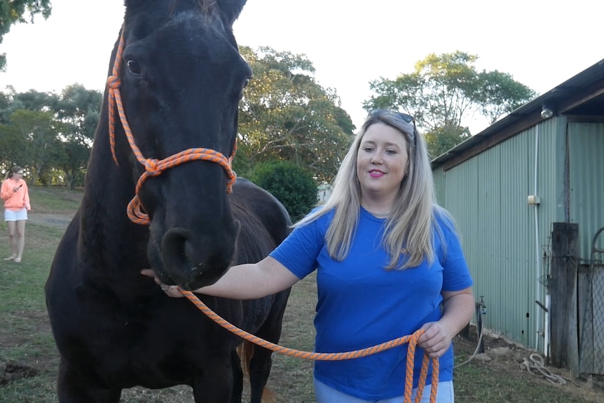 Zoe holds her horse's bridle.