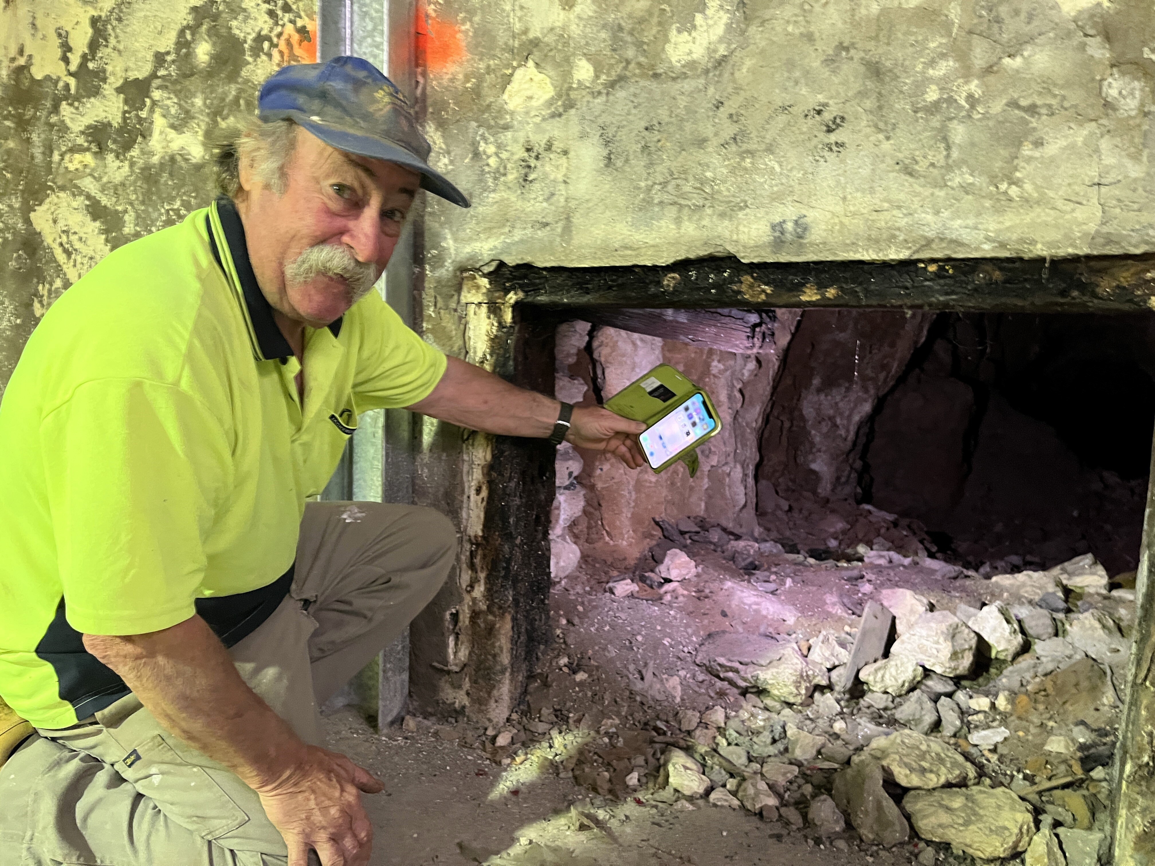 A man leans next to a low tunnel.