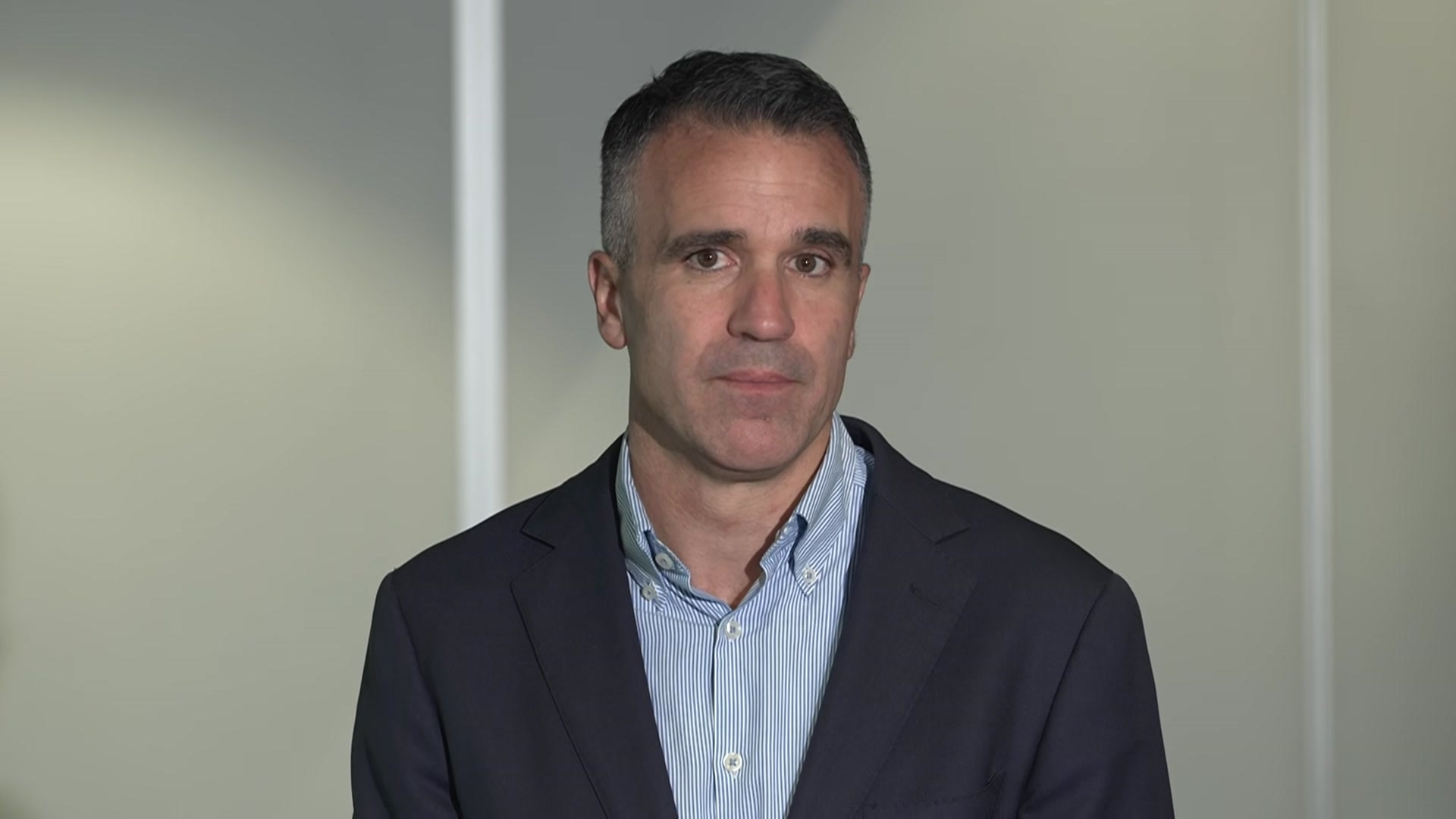 A man in a dark blazer and blue shirt 