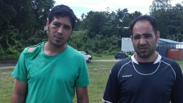 The bashed asylum seekers stand outside the Manus Island police station.