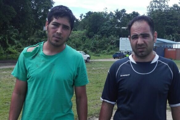 The bashed asylum seekers stand outside the Manus Island police station.