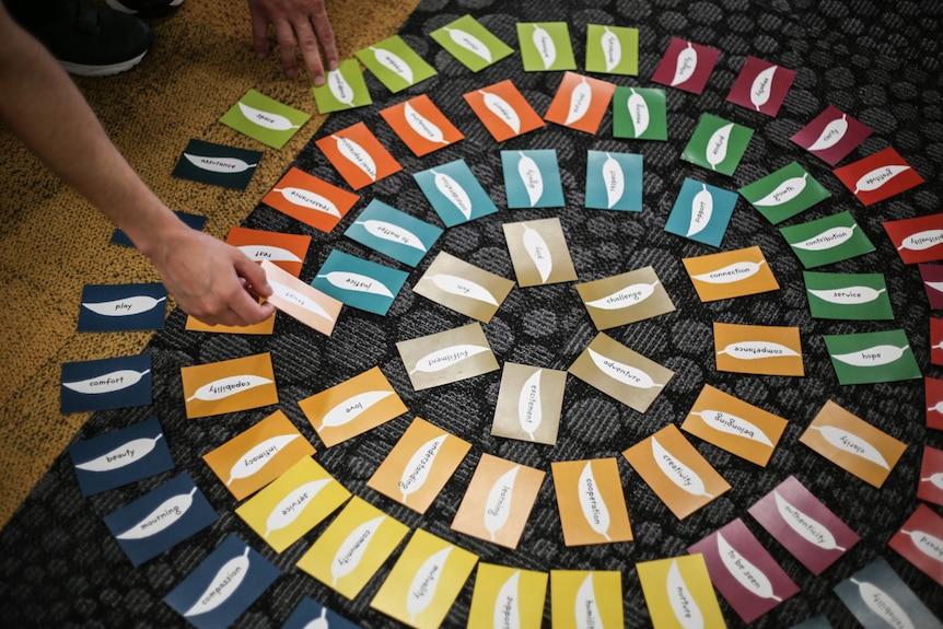 A circle of cards with one card being picked up by a prisoner.
