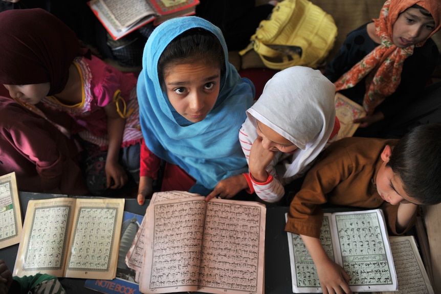 Girls in burqa are reading books in a foreign language.