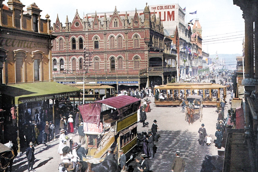 A colourised photograph of the busy Beehive Corner, in Adelaide, 1909, featuring horse-drawn carriages and people wearing hats.