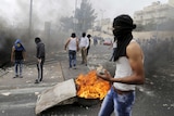 A masked Palestinian holds stones during clashes with Israeli police