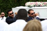 Two men in sunglasses carry a white coffin