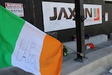 An Irish flag and several bunches of flowers lie outside the entrance to Jaxon construction's East Perth site.