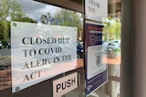 Sign saying closed due to COVID on a shop door. 