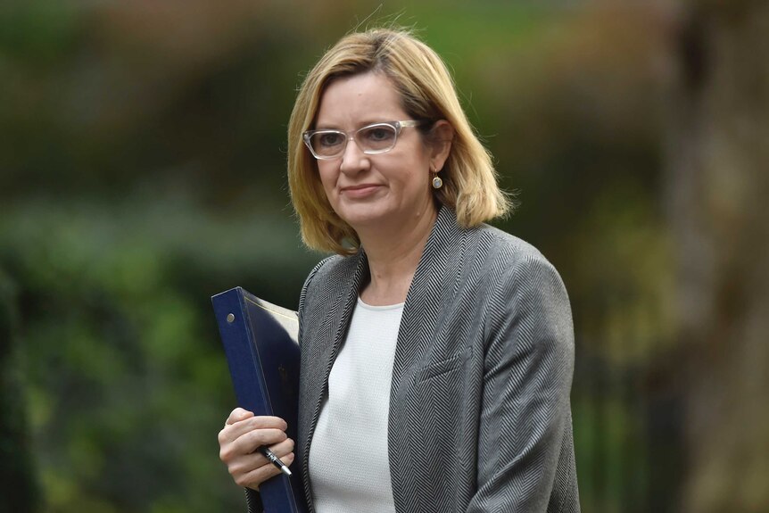 A photo of Amber Rudd holding a folder against an out-of-focus background.