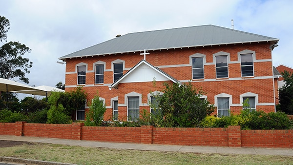 Red brick school building with crucifix at entrance 