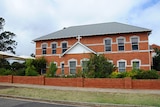 Red brick school building with crucifix at entrance 