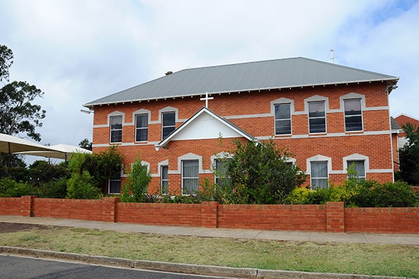 A red brick school building with a crucifix above the entrance.