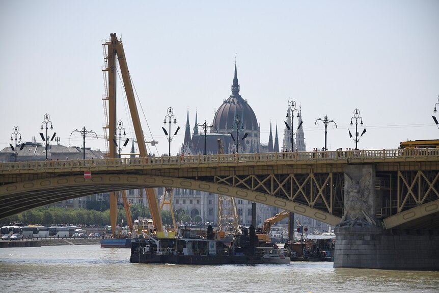 A giant floating crane moves into position near a bridge as its prepares to hoist the wreckage of a sunken tourist boat.