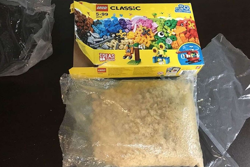 A Lego box and a bag of a light-brown crystal substance.
