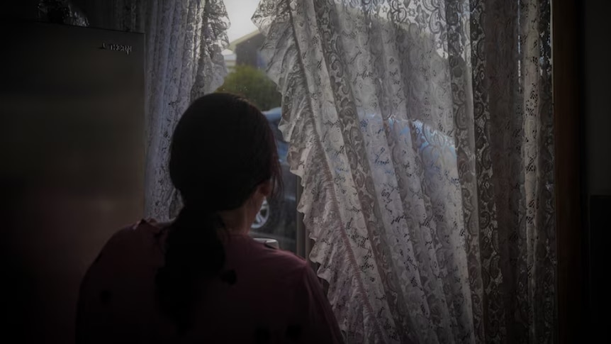 An unidentified woman looks out a window.
