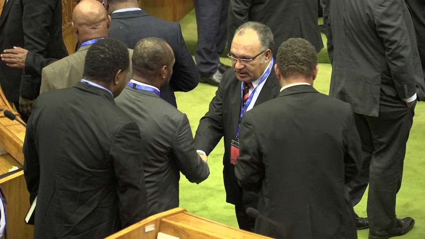 Tight shot of men in suits shaking hands in Parliament.