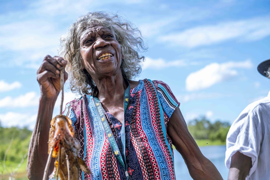 May Nango holds up a fish she caught in Magela Creek.