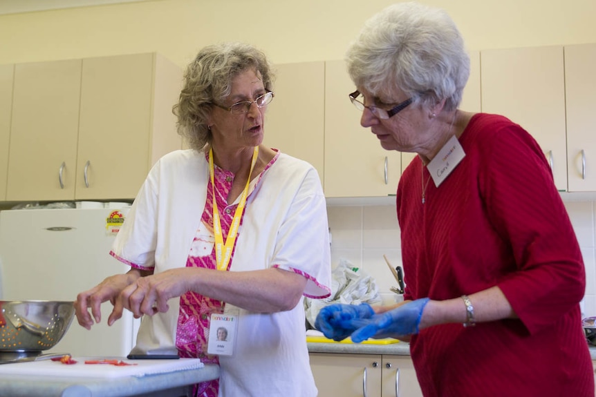 Chef Ann-Marie Jeffares instructs an elderly woman at the Cooking for One or Two program