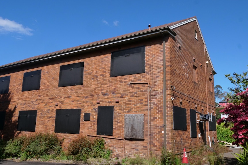 A boarded-up red brick building.