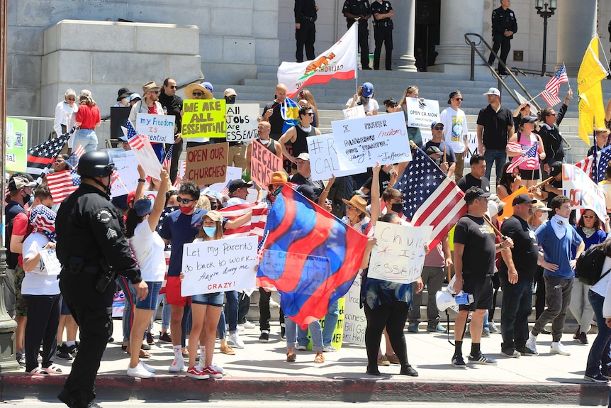 People hold placards and posters as they protest in Sacramento, California.