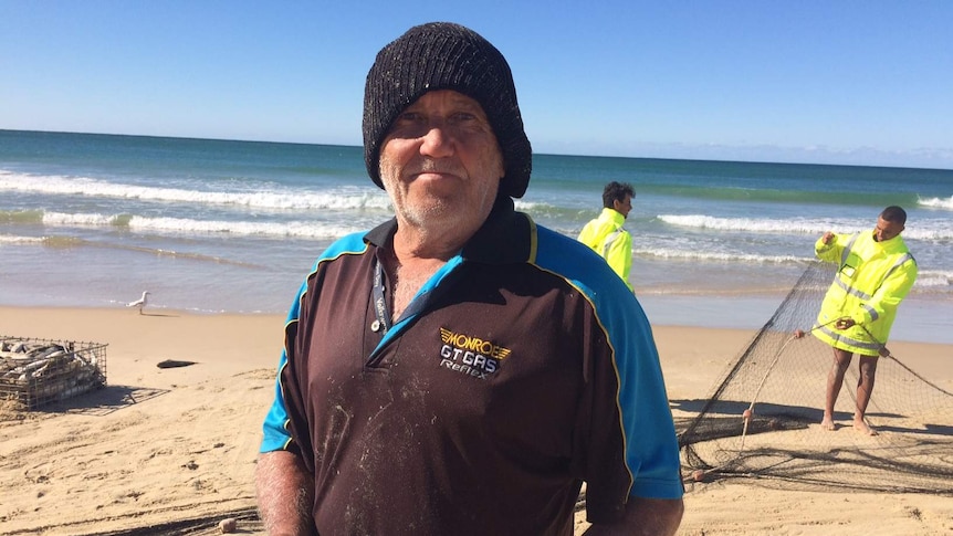 Commercial fisherman on Port Macquarie beach holding a mullet