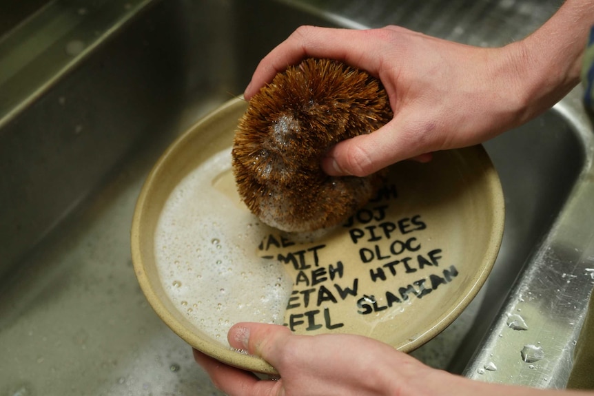 Hand washes bowl with scourer