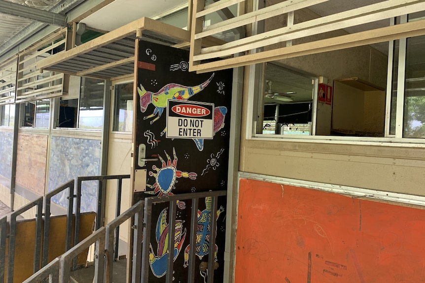 a 'danger do not enter' can be seen on the door of a classroom adorned with indigenous art 