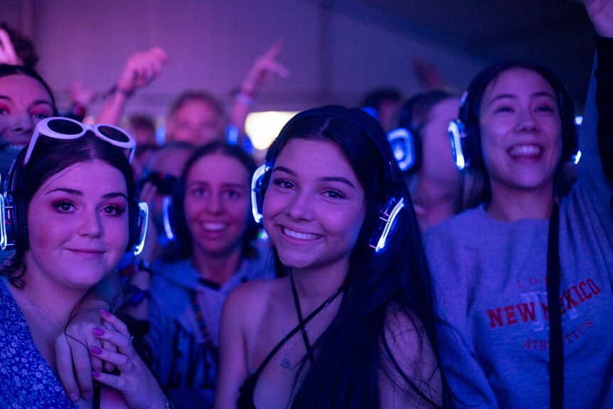 A group of girls dance with headphones on at a silent disco event