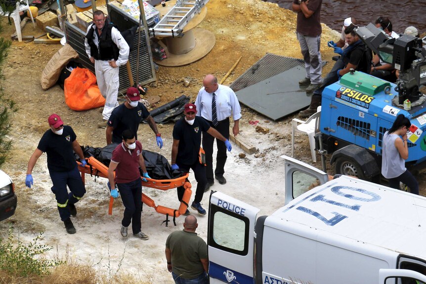 Cyprus Special Disaster Response Unit investigators carry a covered suitcase on a stretcher.