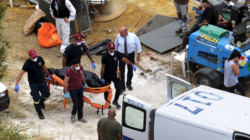 Cyprus Special Disaster Response Unit investigators carry a covered suitcase on a stretcher.