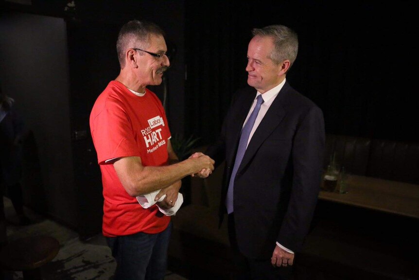 Bill Shorten shakes hand with a man wearing a red Labor t-shirt.