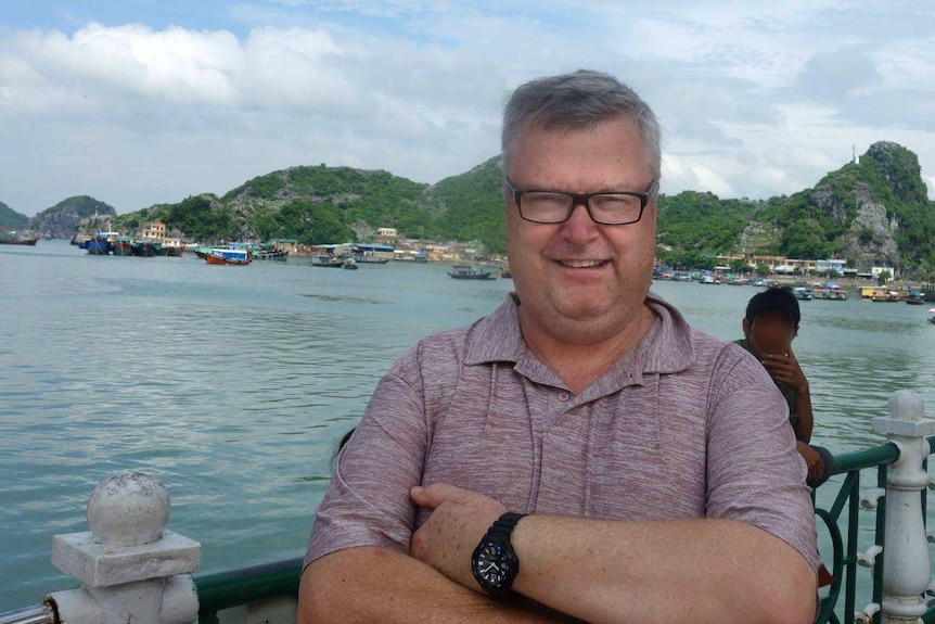 man smiling in front of vietnamese lake