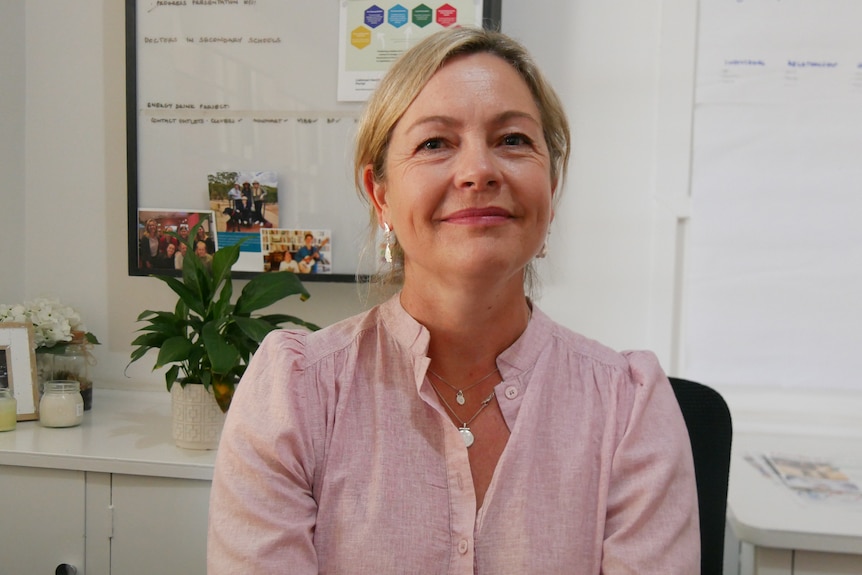 A woman with blonde hair sits in an office. 