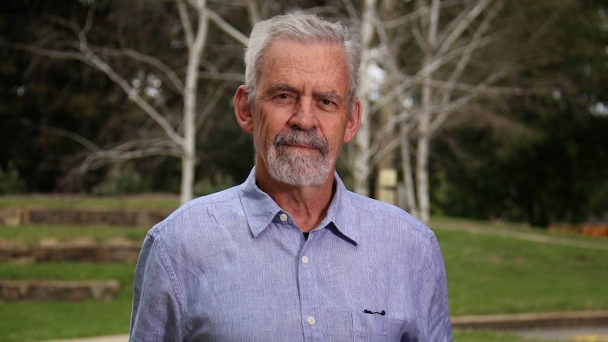 A mature-aged man with grey hair and a button up shirt. 