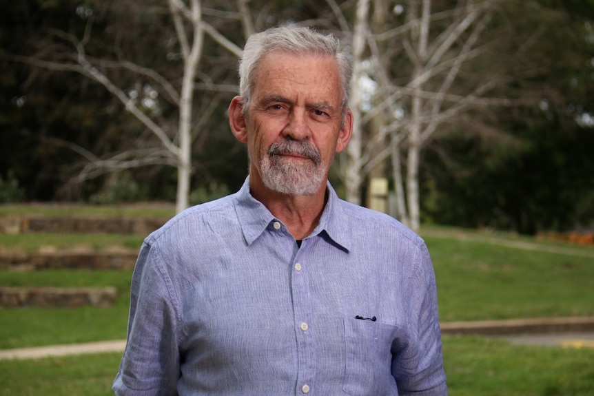 A mature-aged man with grey hair and a button up shirt. 
