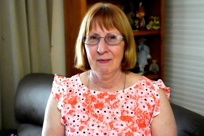 A middle-aged woman wearing glasses and a floral dress poses for a head-and-shoulders photo.