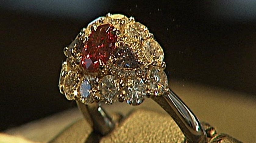 The platinum ring holds a rare fancy purple-red diamond.