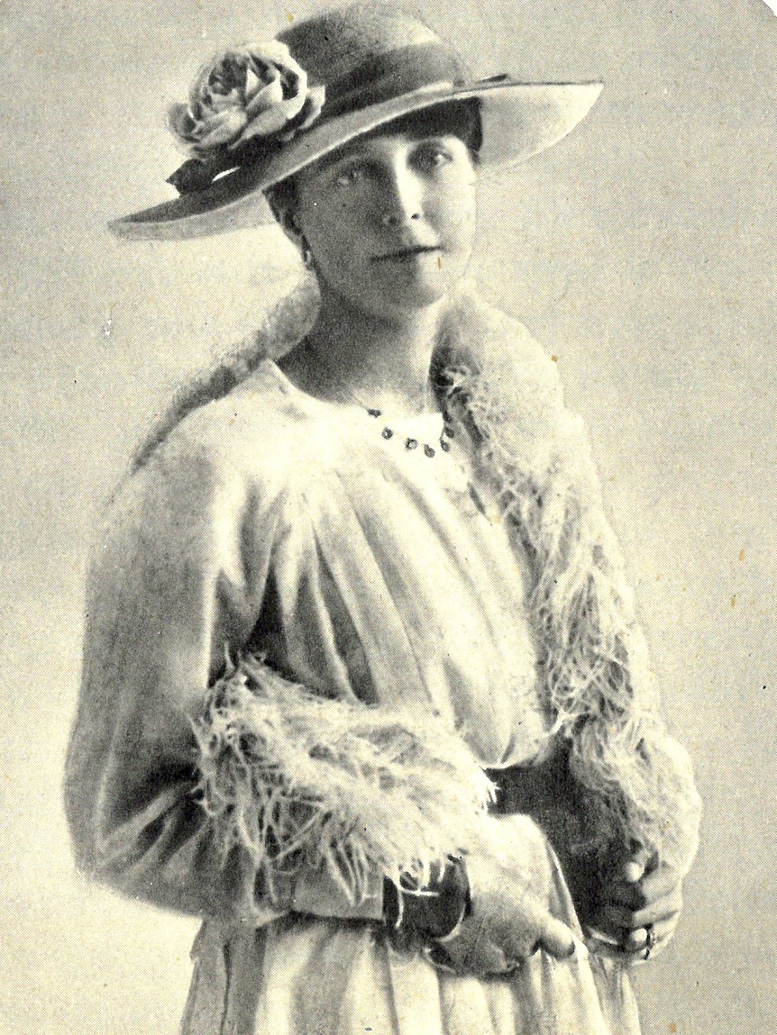 A black and white portrait of a woman in a hat and dress.
