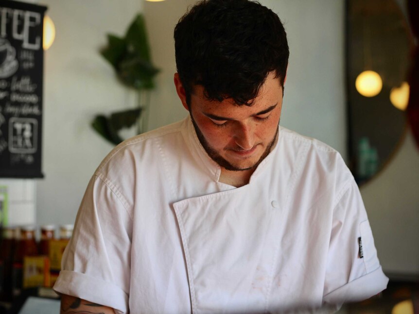 A man in chef's uniform prepares food.
