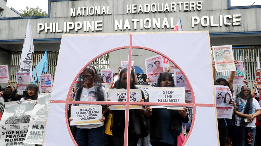Veiled protesters display placards during a protest outside the Philippine national police HQ.