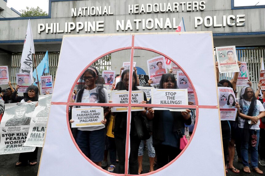 Veiled protesters display placards during a protest outside the Philippine national police HQ.