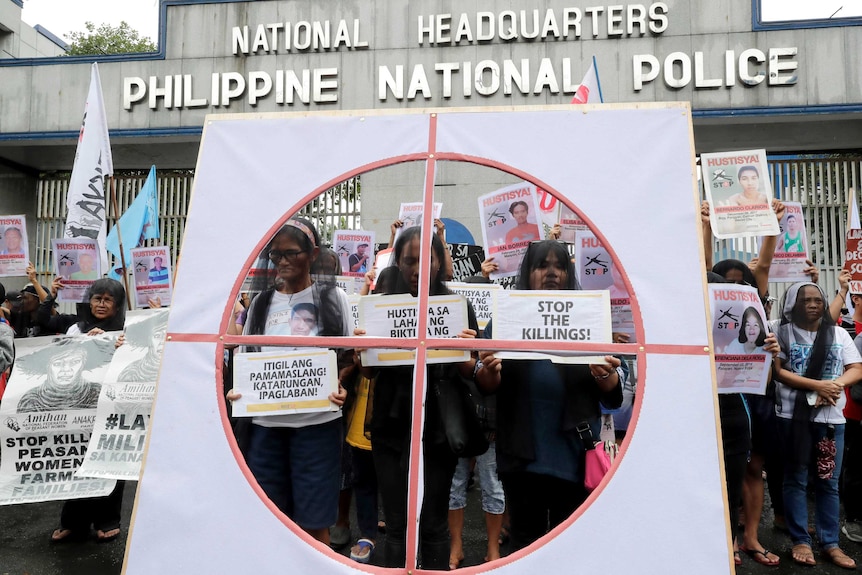 Veiled protesters display placards during a protest outside the Philippine national police HQ.