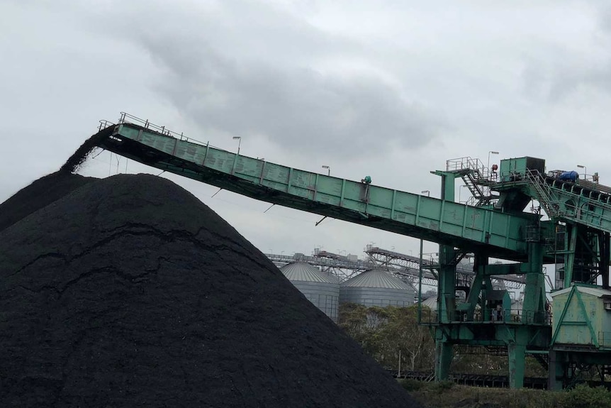 Grey clouds loom above ship-loading machinery in operation at the Port Kembla Coal Terminal in New South Wales.