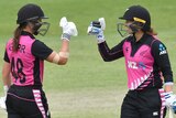 Two New Zealand female cricketers prepare to bump fists as they celebrate beating Australia in Brisbane.